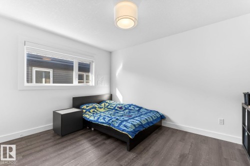 Spacious room featuring wood-finish flooring, a contemporary ceiling light fixture, and a large window with white trim - 793 Windermere Wynd, Edmonton, AB - Indoor Photo Showing Bedroom