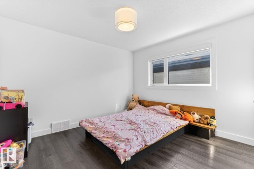Room featuring a contemporary light fixture, a horizontal window with white trim, dark wood-finish flooring, and white baseboards - 793 Windermere Wynd, Edmonton, AB - Indoor Photo Showing Bedroom