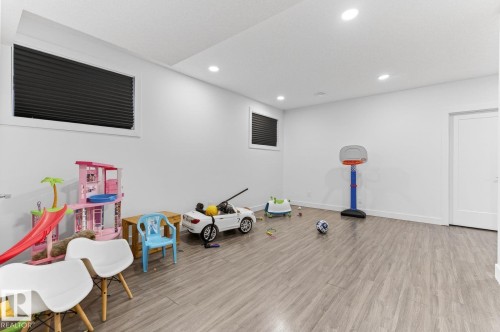 Spacious room featuring wood-finish flooring, recessed lighting, white walls, and two window openings with dark blinds - 793 Windermere Wynd, Edmonton, AB - Indoor Photo Showing Other Room