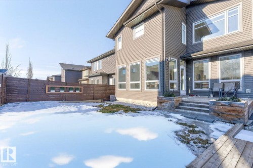 Expansive backyard featuring a privacy fence, multiple windows, and a raised patio - 793 Windermere Wynd, Edmonton, AB - Outdoor