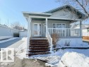 The property features a front porch with white railings and wood-toned steps, a light-colored siding exterior, and a paved driveway leading to a garage - 1741 Jubilee Loop, Sherwood Park, AB  - Outdoor With Deck Patio Veranda 