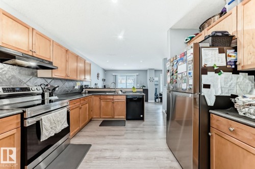 Kitchen featuring wood cabinetry, stainless steel appliances, dark countertops, and a tiled backsplash - 715 Hudson Place, Edmonton, AB - Indoor Photo Showing Kitchen