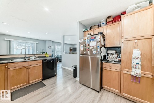 Kitchen featuring wood-finish cabinetry, stainless steel refrigerator, and black dishwasher - 715 Hudson Place, Edmonton, AB - Indoor Photo Showing Kitchen With Double Sink
