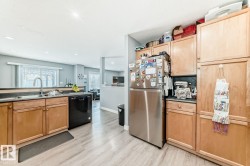 Kitchen featuring wood-finish cabinetry, stainless steel refrigerator, and black dishwasher - 