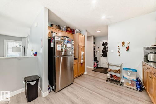 Kitchen featuring wood-finish flooring, light wood cabinetry, stainless steel refrigerator, and recessed lighting - 715 Hudson Place, Edmonton, AB - Indoor