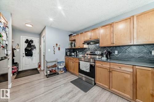 Kitchen featuring light wood cabinetry, dark countertops, and a full suite of stainless steel appliances - 715 Hudson Place, Edmonton, AB - Indoor Photo Showing Kitchen