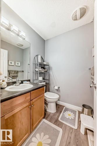 Bathroom featuring a wood-finish vanity with an integrated sink, dark countertop, and brushed nickel faucet - 715 Hudson Place, Edmonton, AB - Indoor Photo Showing Bathroom