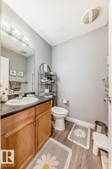 Bathroom featuring a wood-finish vanity with an integrated sink, dark countertop, and brushed nickel faucet - 