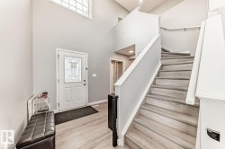 Bright entryway featuring a decorative glass front door, high ceilings, and light wood-finish flooring - 