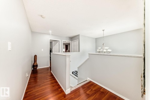 Upper-level hallway with wood-finish flooring, light gray wall paint, and white trim - 715 Hudson Place, Edmonton, AB - Indoor Photo Showing Other Room