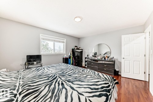 Room featuring wood-finish flooring, a white paneled door, and a single window providing natural light - 715 Hudson Place, Edmonton, AB - Indoor Photo Showing Bedroom