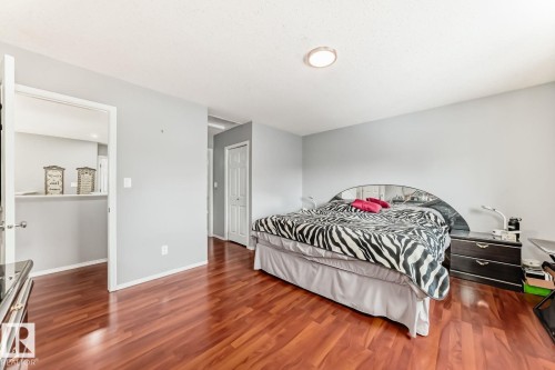 Spacious room featuring wood-finish flooring, light grey walls, a ceiling-mounted light fixture, and a white interior door - 715 Hudson Place, Edmonton, AB - Indoor Photo Showing Bedroom