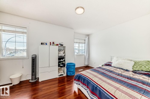 Bedroom featuring rich wood-finish flooring, white walls, and two multi-pane windows with blinds - 715 Hudson Place, Edmonton, AB - Indoor Photo Showing Bedroom