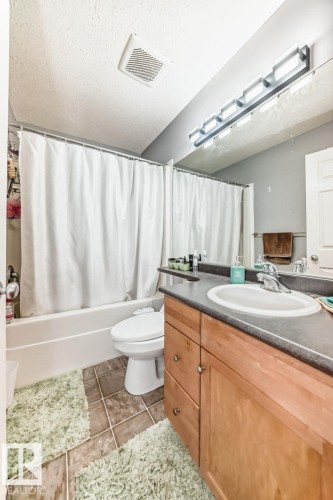 Bathroom featuring a single vanity with wood-finish cabinetry, a white basin, and a dark countertop - 715 Hudson Place, Edmonton, AB - Indoor Photo Showing Bathroom