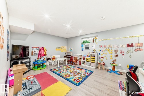 Spacious room featuring light wood-finish flooring, recessed lighting, a single window, light gray wall paint, and a soffit detail - 715 Hudson Place, Edmonton, AB - Indoor Photo Showing Other Room