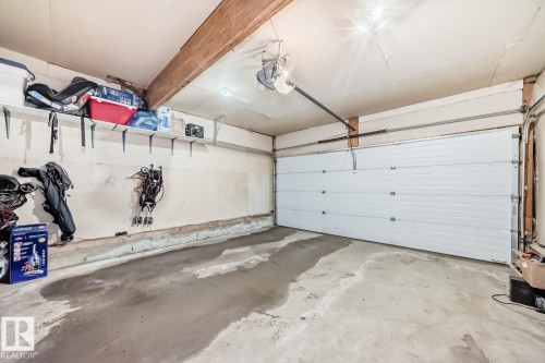 Single-car garage featuring a white panel door, concrete flooring, and an exposed wood beam ceiling - 715 Hudson Place, Edmonton, AB - Indoor Photo Showing Garage