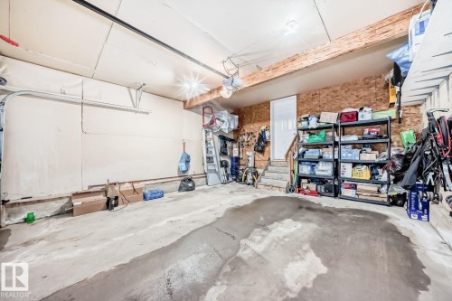 Functional garage space featuring a concrete floor, overhead lighting, and built-in shelving - 715 Hudson Place, Edmonton, AB - Indoor Photo Showing Garage