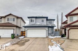 Two-story property featuring light gray siding, an attached double-car garage, and a concrete driveway - 