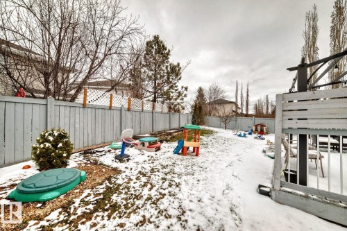 Fenced backyard featuring a gravel-edged shrub, a spacious lawn area, and a built-in outdoor structure with white railings - 715 Hudson Place, Edmonton, AB - Outdoor