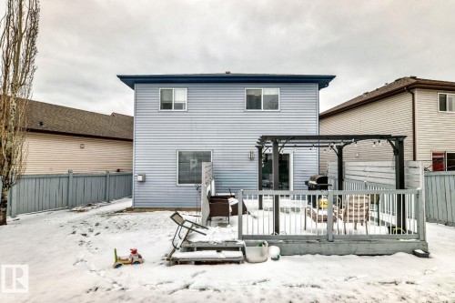 Rear exterior featuring light blue siding, a multi-level wood-finish deck with railing, and a dark-toned pergola - 715 Hudson Place, Edmonton, AB - Outdoor With Exterior