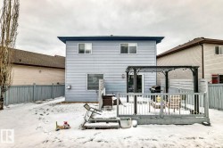 Rear exterior featuring light blue siding, a multi-level wood-finish deck with railing, and a dark-toned pergola - 