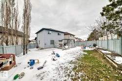 Expansive backyard featuring a multi-level wood deck, raised garden beds, and full perimeter fencing - 