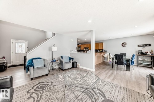 Expansive living area featuring light wood-finish flooring, recessed lighting, and a white front entry door with decorative glass - 715 Hudson Place, Edmonton, AB - Indoor