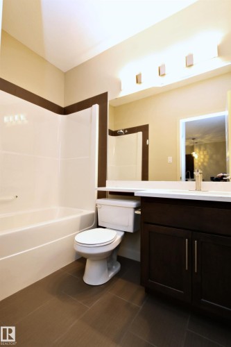 Bathroom featuring a dark wood-finish vanity, white countertop, and integrated sink - 140 308 Ambleside Link Link Sw, Edmonton, AB - Indoor Photo Showing Bathroom