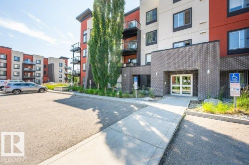 Contemporary building exterior featuring red, white, and gray paneling with dark brick accents - 140 308 Ambleside Link Link Sw, Edmonton, AB - Outdoor With Facade