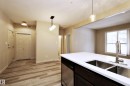 Kitchen island with a white solid surface countertop and undermount stainless steel sinks - 140 308 Ambleside Link Link Sw, Edmonton, AB  - Indoor Photo Showing Kitchen With Double Sink 