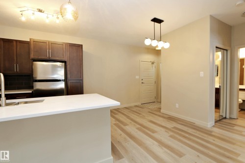 Open-concept living area with light wood-finish flooring - 140 308 Ambleside Link Link Sw, Edmonton, AB - Indoor Photo Showing Kitchen