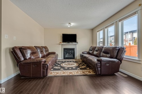 Living area featuring dark wood-finish flooring, light neutral-toned walls, and a recessed fireplace with a white mantel - 2314 22 Avenue, Edmonton, AB - Indoor Photo Showing Living Room With Fireplace