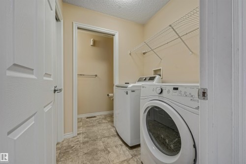 Dedicated laundry area featuring a front-loading washing machine, top-loading washing machine, and overhead wire shelving - 2314 22 Avenue, Edmonton, AB - Indoor Photo Showing Laundry Room