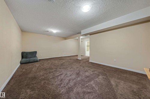 Spacious room featuring brown carpet flooring, neutral-toned walls, and a textured ceiling - 2314 22 Avenue, Edmonton, AB - Indoor Photo Showing Other Room