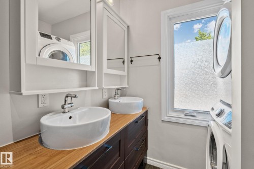 Dual vessel sinks atop a wood-finish countertop - 13635 108 Avenue, Edmonton, AB - Indoor Photo Showing Bathroom