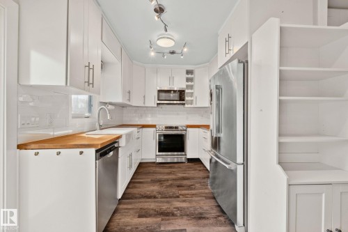 Bright kitchen featuring white cabinetry, wood-finish countertops, and stainless steel appliances - 13635 108 Avenue, Edmonton, AB - Indoor Photo Showing Kitchen With Upgraded Kitchen