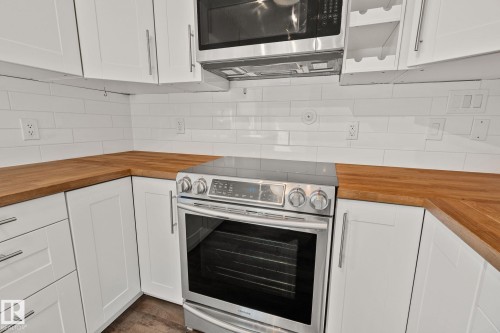 Modern kitchen featuring white shaker cabinetry, wood-finish countertops, and a white subway tile backsplash - 13635 108 Avenue, Edmonton, AB - Indoor Photo Showing Kitchen