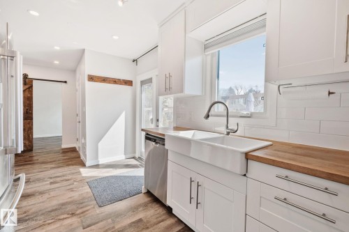 Kitchen featuring white cabinetry, wood-finish countertops, a farmhouse sink, stainless steel appliances, and wood-finish flooring - 13635 108 Avenue, Edmonton, AB - Indoor Photo Showing Kitchen With Upgraded Kitchen