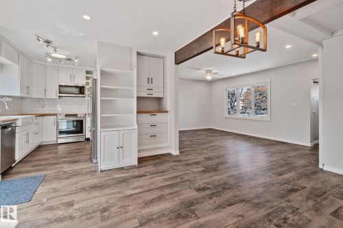 Open concept living area featuring wood-finish flooring, recessed lighting, and a decorative exposed beam with a modern chandelier - 13635 108 Avenue, Edmonton, AB - Indoor Photo Showing Kitchen