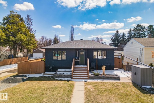Modern bungalow featuring a dark exterior, a wood entry staircase, and a manicured front lawn - 13635 108 Avenue, Edmonton, AB - Outdoor With Deck Patio Veranda