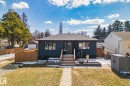 Modern bungalow featuring a dark exterior, a wood entry staircase, and a manicured front lawn - 13635 108 Avenue, Edmonton, AB  - Outdoor With Deck Patio Veranda 
