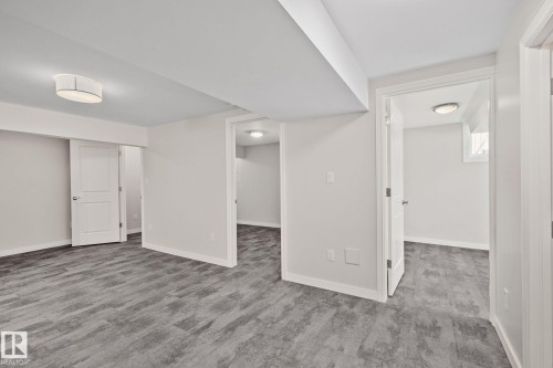 Spacious interior featuring wood-finish flooring, light grey wall tones, recessed lighting, and multiple doorways - 13635 108 Avenue, Edmonton, AB - Indoor Photo Showing Other Room