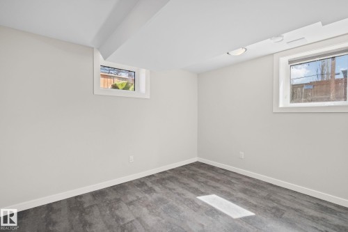 Bright interior space featuring light grey walls, white trim, and dark wood-finish flooring - 13635 108 Avenue, Edmonton, AB - Indoor Photo Showing Other Room