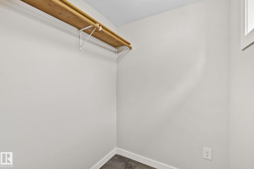 Walk-in closet with light wood shelving, white walls, and a gray floor - 13635 108 Avenue, Edmonton, AB - Indoor