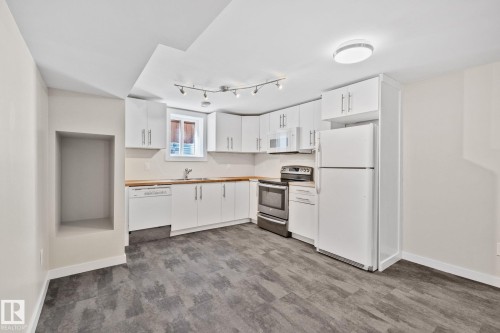 Kitchen area featuring white cabinetry, wood-finish countertops, and a full suite of appliances - 13635 108 Avenue, Edmonton, AB - Indoor Photo Showing Kitchen