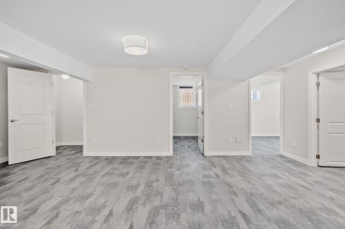 Spacious interior featuring wood-finish flooring, white walls, recessed lighting, white doors, and a flush mount ceiling light - 13635 108 Avenue, Edmonton, AB - Indoor Photo Showing Other Room