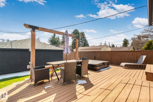 Spacious wood-plank deck featuring a built-in hot tub, privacy fence, and a wooden pergola structure - 13635 108 Avenue, Edmonton, AB - Outdoor With Deck Patio Veranda