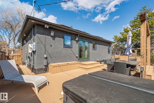 Expansive wood-finish deck featuring tiered steps, built-in storage bench, and dark stucco exterior - 13635 108 Avenue, Edmonton, AB - Outdoor With Deck Patio Veranda With Exterior