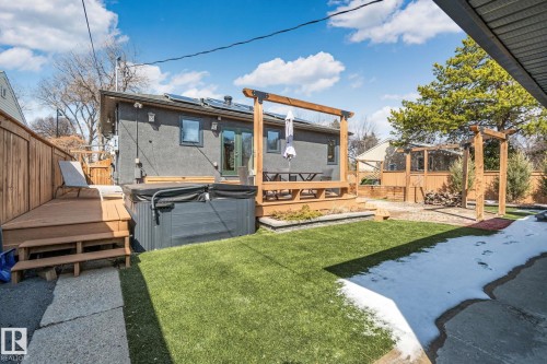 Private backyard oasis featuring a hot tub, artificial turf, and a multi-level wood deck with pergola - 13635 108 Avenue, Edmonton, AB - Outdoor With Deck Patio Veranda