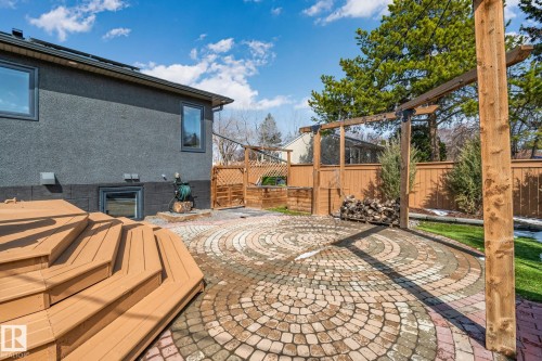 Spacious backyard featuring a multi-level wood-tone deck, circular paver patio, wood pergola structure, and privacy fencing - 13635 108 Avenue, Edmonton, AB - Outdoor